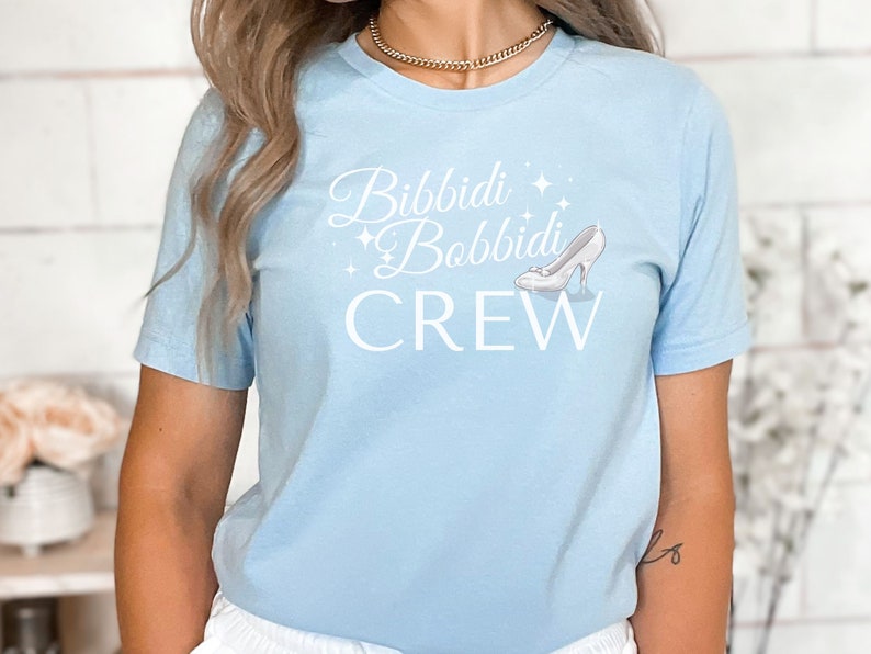 May include: Light blue t-shirt with a white graphic that says "Bibbidi Bobbidi Crew" with a glass slipper graphic.