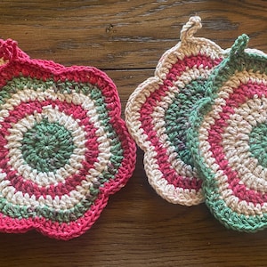 May include: Four crocheted pot holders in a flower shape with green, white, and pink stripes.