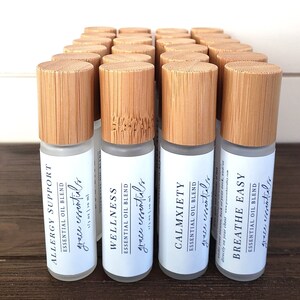 May include: Twenty-four 1/3 ounce roll-on bottles with bamboo caps and white labels. The labels have the text "grace essentials" and the names of different essential oil blends: "Allergy Support", "Wellness", "Calmxiety", and "Breathe Easy".