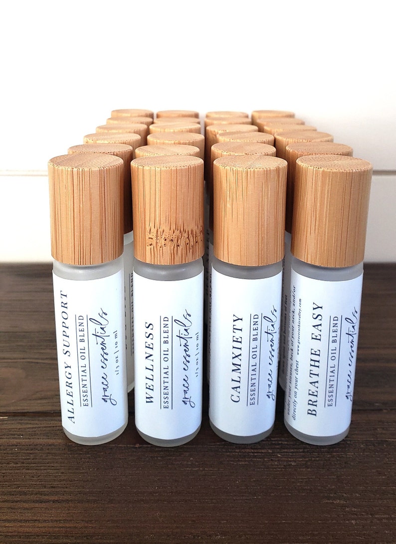 May include: Twenty-four 1/3 ounce roll-on bottles with bamboo caps and white labels. The labels have the text "grace essentials" and the names of different essential oil blends: "Allergy Support", "Wellness", "Calmxiety", and "Breathe Easy".