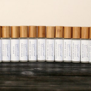 May include: A row of 30 small, clear glass bottles with bamboo caps. The bottles are labeled with the text "Groundwood" and "Naturally Scented".