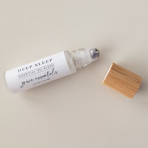 May include: A white roller bottle with a clear glass roller ball and a bamboo cap. The label reads "DEEP SLEEP ESSENTIAL OIL BLEND grace essentials 1/3 oz | 10 ml".