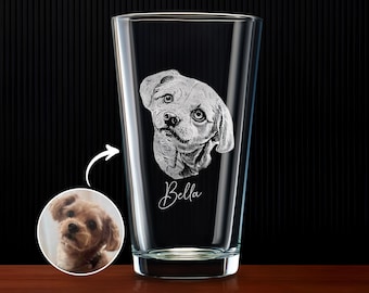 May include: A clear glass pint glass with a detailed etched portrait of a dog's face. The dog's name, "Bella," is written in cursive below the portrait. A small circular image of the dog is next to the glass.