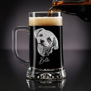 May include: A clear glass beer mug with a handle, filled with dark beer and foam. The mug features an etched image of a dog's face and the name "Bella" in cursive. Beer is being poured from a bottle.