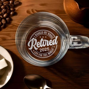 May include: A clear glass mug with a handle, filled with liquid. The mug has an etched design that reads "I worked my whole life for this moment - Retired 2025".