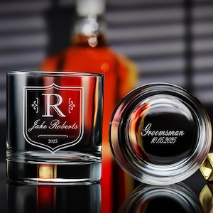 May include: Two clear glass tumblers with engraved text. The first tumbler has a shield with the letter "R" and the text "Jake Roberts 2025". The second tumbler has the text "Groomsman 10.05.2025".
