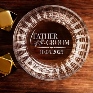 以下が含まれることがあります： 装飾的なパターンと「Father of the Groom」の刻印、および「10.05.2025」の日付が刻まれた透明なガラス製の灰皿です。
