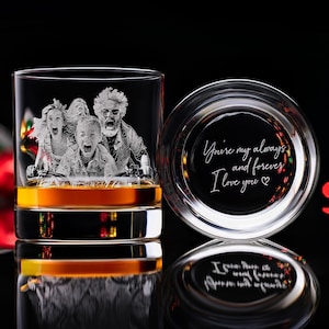 May include: A clear whiskey glass with a family portrait etched on the side, filled with amber liquid. The glass is next to its lid, which has the inscription "You're my always and forever, I love you".