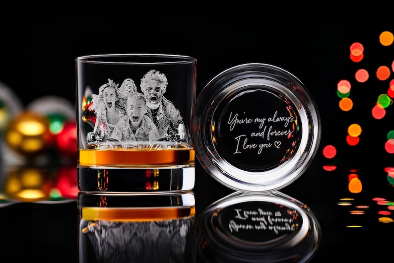 May include: A clear whiskey glass with a family portrait etched on the side, filled with amber liquid. The glass is next to its lid, which has the inscription "You're my always and forever, I love you".