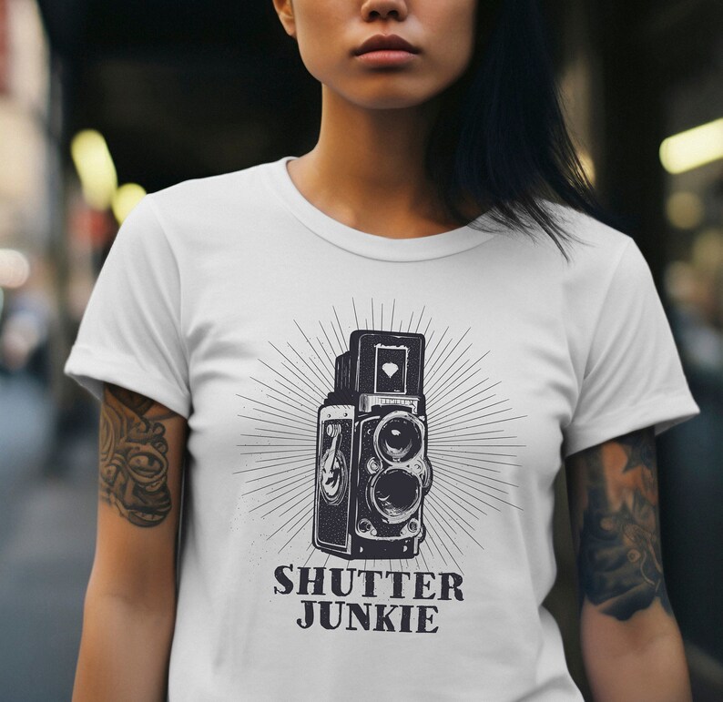 White t-shirt showcasing a retro camera graphic and "Shutter Junkie" text.