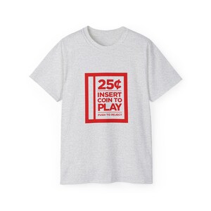 Woman smiling while wearing a white t-shirt with a retro arcade game theme, featuring a "25¢ Insert Coin to Play" design