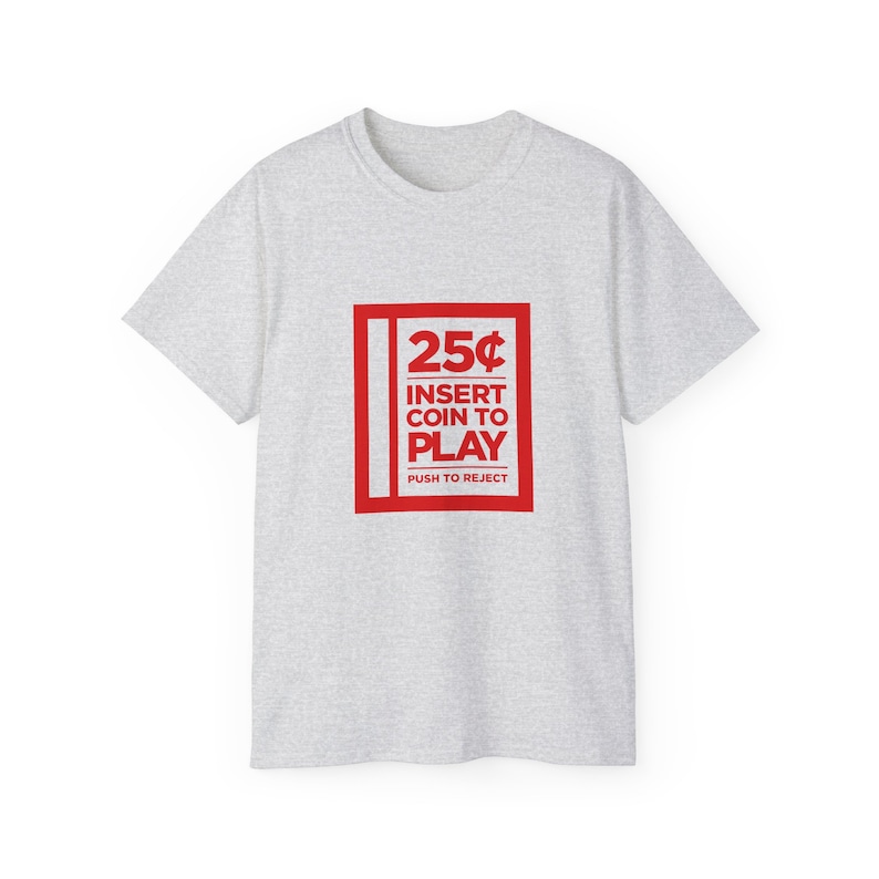 Woman smiling while wearing a white t-shirt with a retro arcade game theme, featuring a "25¢ Insert Coin to Play" design