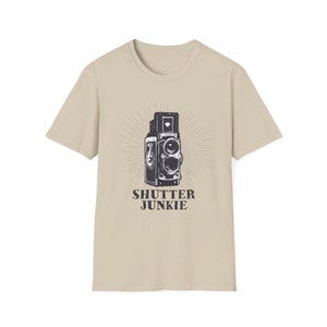 Beige t-shirt showcasing a vintage camera design and "Shutter Junkie" text.