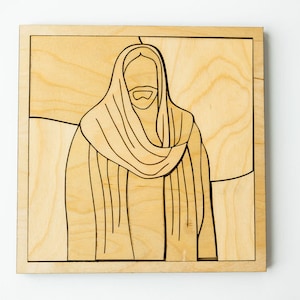 May include: Wooden jigsaw puzzle depicting a line drawing of a robed figure with a beard. The puzzle is made of light-coloured wood with a natural grain, and the image is outlined in black. The puzzle is square in shape.