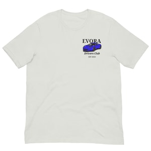 Könnte beinhalten: Weißes T-Shirt mit einer kleinen Grafik eines blauen Sportwagens und dem Wort "EVORA" darüber. Unter dem Auto steht der Text "Drivers Club EST 2010". Das T-Shirt hat kurze Ärmel und einen Rundhalsausschnitt.