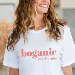 May include: White t-shirt with the text "boganic and banging" printed in pink.