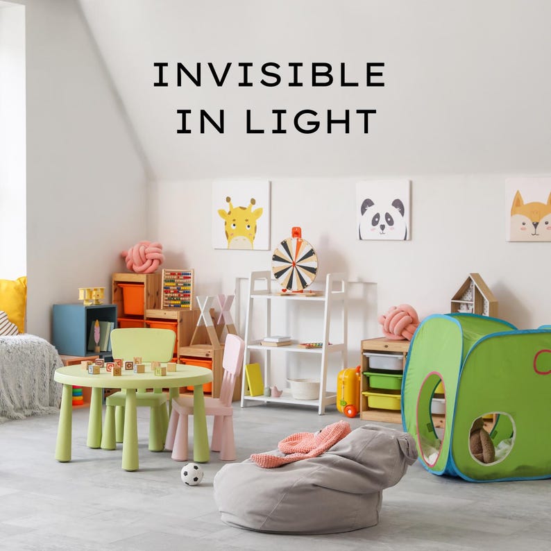 May include: A child's playroom with a green table and chairs, a gray beanbag chair, and a green and blue play tent. The room also features artwork of animals and the text "INVISIBLE IN LIGHT".
