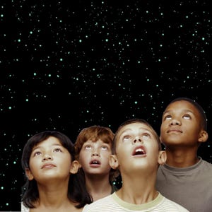 May include: Four children of diverse ethnicities gaze upward with expressions of wonder. The background is a black expanse dotted with small, light green stars. The children are looking up at the stars.