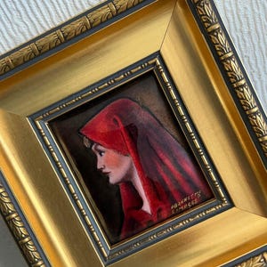 May include: A framed portrait of a woman in a red hood, set against a dark background. The painting is in a gold frame with ornate detailing. The artist's signature, "PBONNETH LIMOGES", is visible.