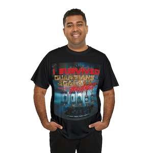 May include: Black t-shirt with a graphic print of the Guardians of the Galaxy Mission: Breakout! ride at Disney World. The text "I Survived" is printed in red above the graphic.