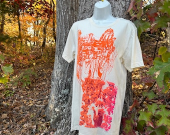 May include: A white t-shirt with a bright orange and pink graphic print of a stylized design. The design features a series of abstract shapes and lines.