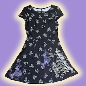 May include: Black skater dress with white roller skate pattern. The dress features a scoop neckline and short sleeves. The skirt has a purple and white graphic design. A stylish and unique dress for casual wear.