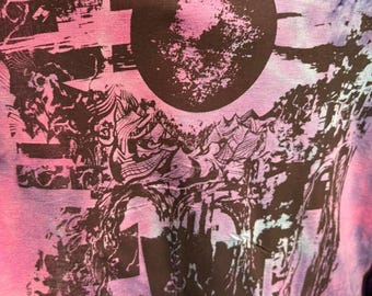Może przedstawiać: Koszulka typu tie-dye w odcieniach różu, fioletu i błękitu. Koszulka ma duży czarny wzór graficzny z okrągłym kształtem i skomplikowanymi wzorami, tworząc unikalny i artystyczny wygląd.