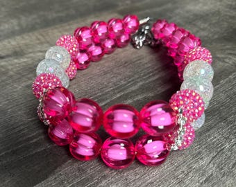 May include: A pink and white beaded necklace with a silver clasp. The necklace is made of large, round beads and smaller, sparkly beads.