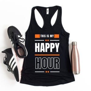 Może przedstawiać: Czarny top bez rękaw&oacute;w z napisem "THIS IS MY HAPPY HOUR" w kolorze białym i pomarańczowym. Obraz zawiera r&oacute;wnież czarno-białe buty sportowe i miedzianą butelkę na wodę.