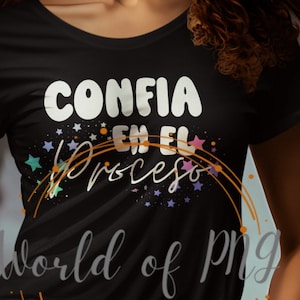 Op de afbeelding: Zwart T-shirt met de Spaanse zin "Confia en el Proceso" in witte letters en een sterrenontwerp. Het shirt heeft ook de tekst "World of PNG" in een cursief lettertype. Het model draagt een blauwe spijkerbroek.