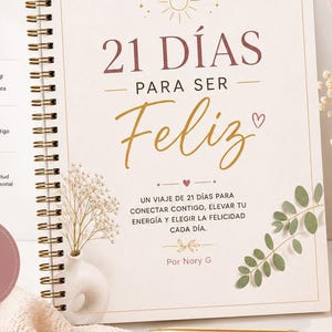 May include: A spiral-bound journal with the title "21 Days to Be Happy" in gold script. The journal is open, displaying text and decorative elements. A cup of coffee, flowers, and a candle are also visible.