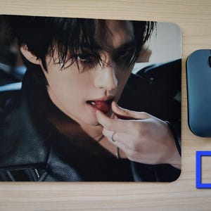 May include: Mouse mat with a close-up image of a person eating a strawberry. A blue wireless mouse is to the right of the mouse mat. The letter "D" is in the lower right corner.