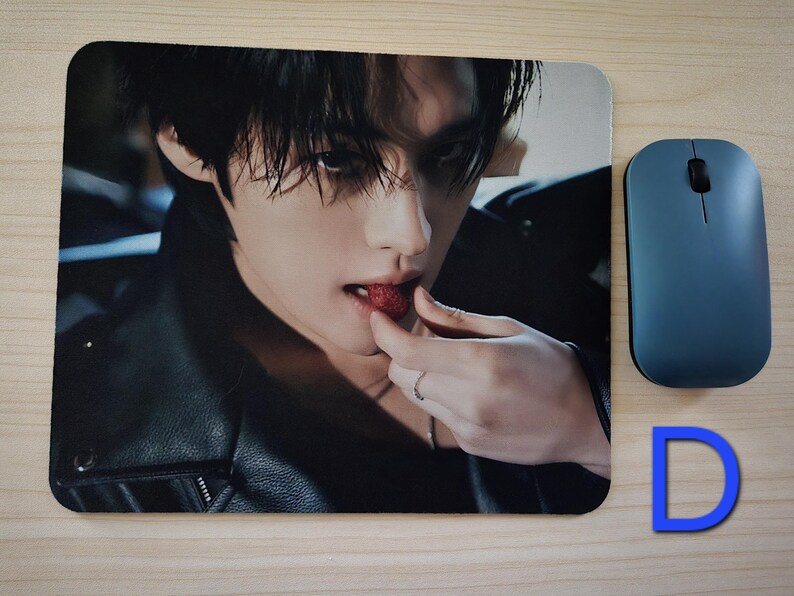 May include: Mouse mat with a close-up image of a person eating a strawberry. A blue wireless mouse is to the right of the mouse mat. The letter "D" is in the lower right corner.