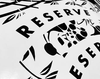 Może przedstawiać: Czarno-białe zdjęcie arkusza z napisem "RESERVE" pogrubioną czcionką bezszeryfową. Arkusz zawiera również stylizowane wzory bambusa i kwiatów. Zdjęcie zrobione jest pod kątem, ukazując powierzchnię arkusza.