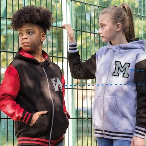 Könnte beinhalten: Zwei Kinder tragen Kapuzenjacken mit Reißverschluss. Einer ist schwarz mit roten Ärmeln und einem weißen und blauen "W"-Aufnäher. Der andere ist grau mit schwarzen Ärmeln und einem grauen und schwarzen "M"-Aufnäher. Beide haben gestreifte Bündchen und einen Reißverschluss.