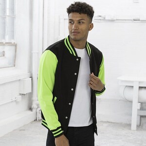 Könnte beinhalten: Schwarze Collegejacke mit neongrünen Ärmeln und Besatz. Die Jacke hat eine Knopfleiste vorne und einen gerippten Kragen und Bündchen. Die Ärmel sind leuchtend neongrün, während der Körper schwarz ist.