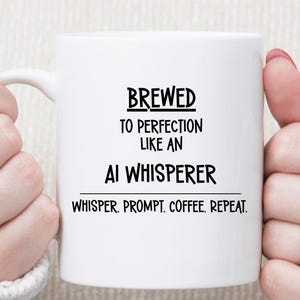 May include: White ceramic coffee mug with the text "BREWED TO PERFECTION LIKE AN AI WHISPERER" in black. Below the text is "WHISPER. PROMPT. COFFEE. REPEAT." The mug is held by two hands.