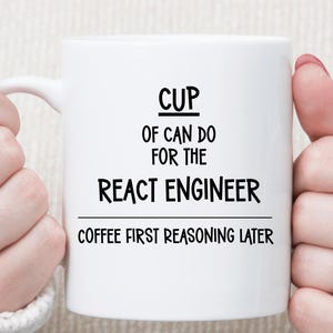 May include: White ceramic mug with the text "CUP OF CAN DO FOR THE REACT ENGINEER COFFEE FIRST REASONING LATER" in black. The mug is held by a person wearing a white sweater. The mug has a handle.