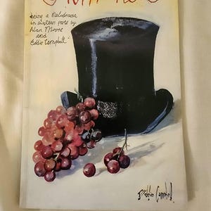 May include: A book cover with the title "From Hell" written in cursive. The cover features a black top hat and a bunch of red grapes. The text below the title reads "being a Melodrama in sixteen parts by Alan Moore and Eddie Campbell."