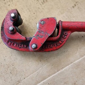 K&ouml;nnte beinhalten: Roter Metall-Rohrschneider mit den Worten "American Pipe Tool Co." auf der Seite.