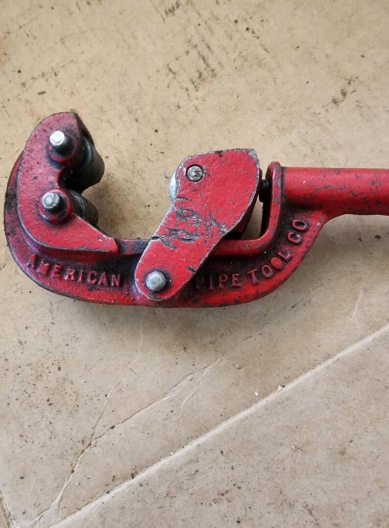 K&ouml;nnte beinhalten: Roter Metall-Rohrschneider mit den Worten "American Pipe Tool Co." auf der Seite.