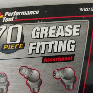 Op de afbeelding: Een verpakking met 70 stuks smeernippel assortiment. De verpakking is zwart met rode en witte tekst. De tekst op de verpakking luidt "Performance Tool" en "70 Piece Grease Fitting Assortment". De verpakking toont een close-up van verschillende smeernippels.