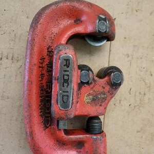 K&ouml;nnte beinhalten: Roter RIDGID-Rohrschneider mit einer Kapazit&auml;t von 48 Zoll. Das Werkzeug ist aus strapazierf&auml;higem Metall gefertigt und hat einen schwarzen Griff.