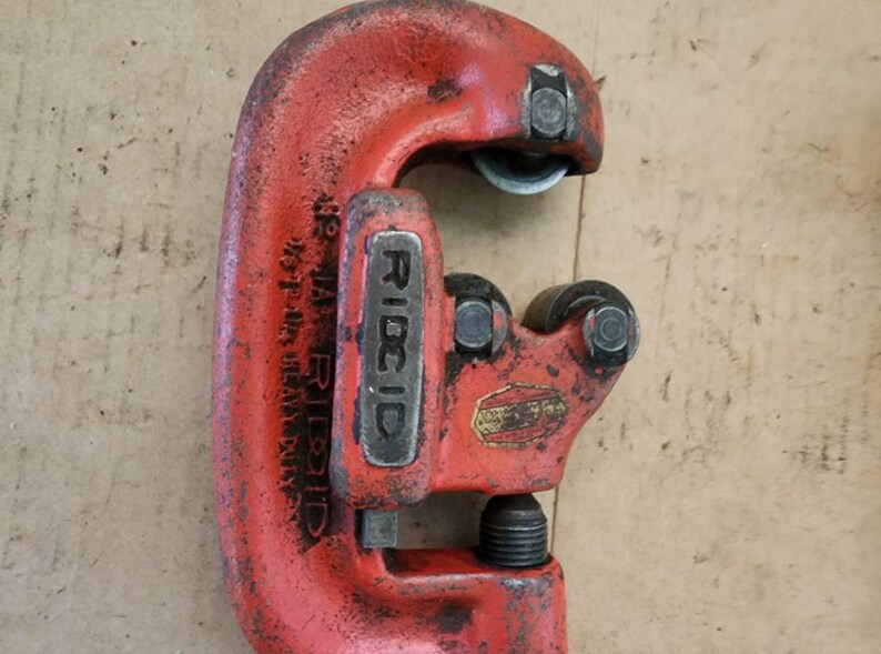 K&ouml;nnte beinhalten: Roter RIDGID-Rohrschneider mit einer Kapazit&auml;t von 48 Zoll. Das Werkzeug ist aus strapazierf&auml;higem Metall gefertigt und hat einen schwarzen Griff.
