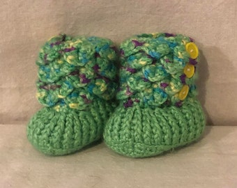 May include: A pair of green crocheted baby booties with colorful accents and yellow buttons.