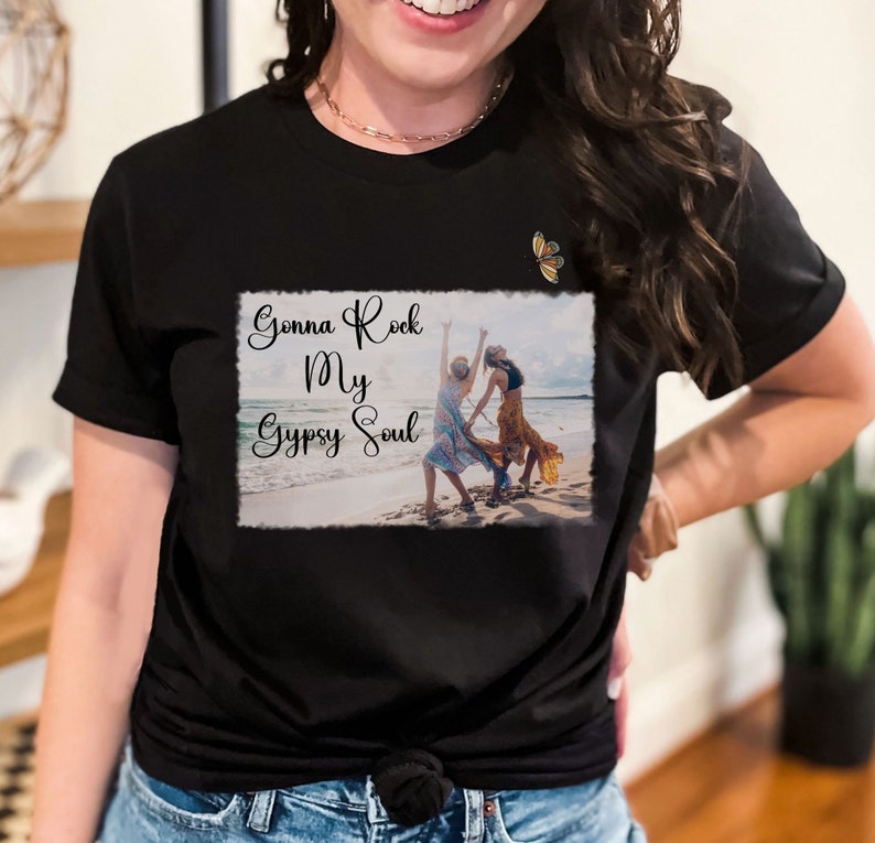 K&ouml;nnte beinhalten: Schwarzes T-Shirt mit einer wei&szlig;en Grafik von zwei Frauen, die am Strand tanzen, mit dem Text "Gonna Rock My Gypsy Soul" in einer verwitterten Schrift.