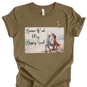 K&ouml;nnte beinhalten: Ein braunes T-Shirt mit einem Aufdruck von zwei Frauen am Strand mit dem Text "Gonna Rock My Gypsy Soul" und einem Schmetterling &uuml;ber dem Aufdruck.