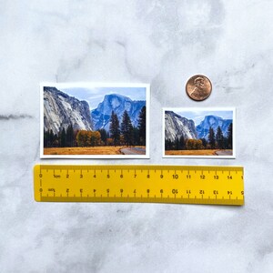May include: Two photographs of Yosemite National Park, one larger than the other. Both photos show a view of Half Dome and a valley with trees and a road.