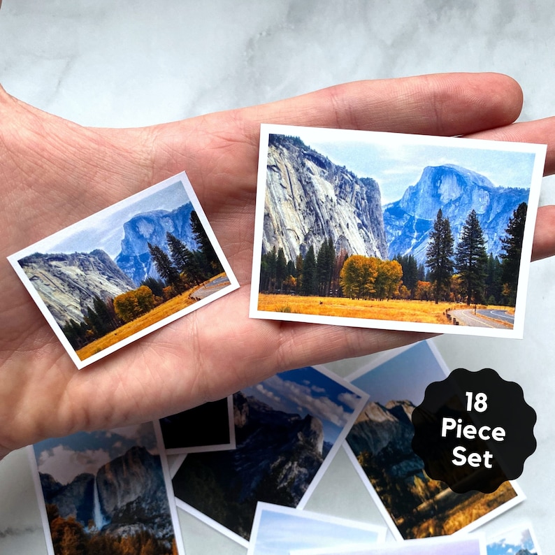 May include: An 18 piece jigsaw puzzle set featuring scenic views of Yosemite National Park. The puzzle pieces are arranged in a hand, showing the different images in the set. The images include a view of Half Dome, El Capitan, and the valley floor.