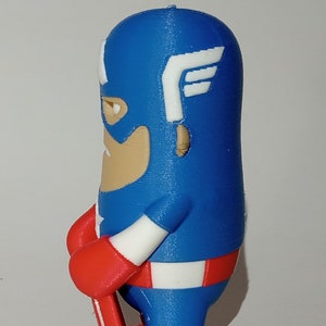 May include: A blue and red 3D printed figurine of Captain America holding a shield. The figurine is in a standing position with its right leg forward. The figurine is wearing a blue and white costume with a red star on the chest. The figurine has a red and white shield in its right hand.